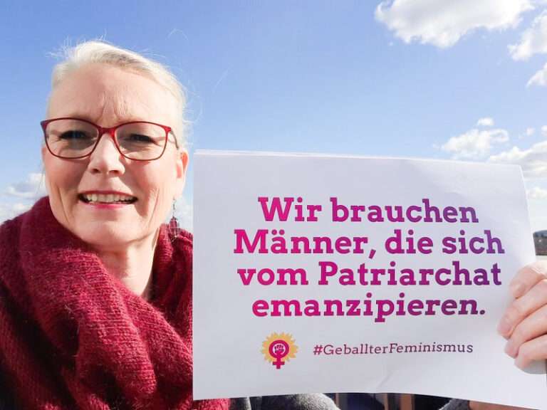 Sonja aus Röbel hält ein Blatt mit der Aufschrift „Wir brauchen Männer, die sich vom Patriarchat emanzipieren" in die Kamera.