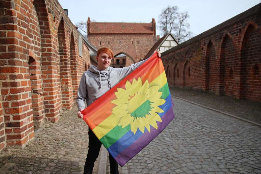 Martin Krell hält eine Regenbogenflagge in den Händen.